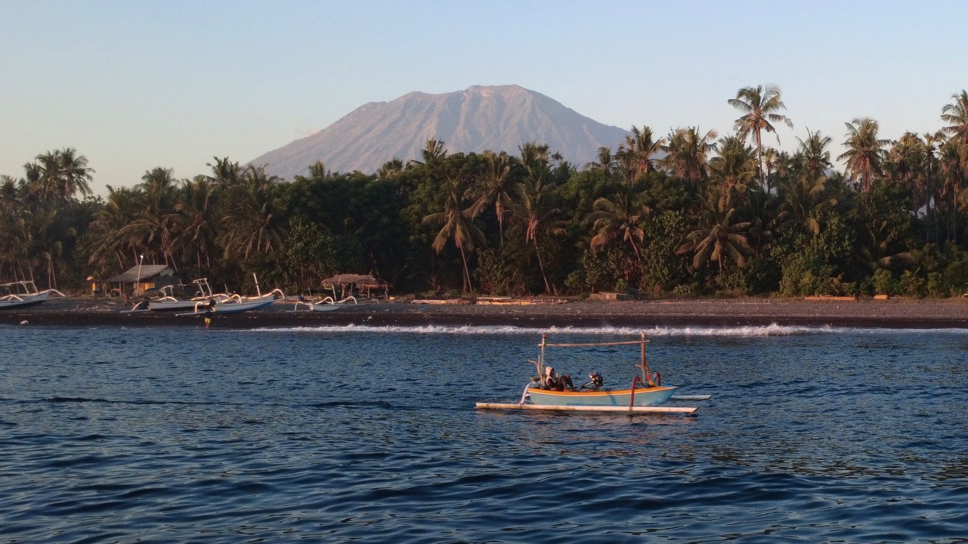 Local fishermen with traditional jukung boat on black sand